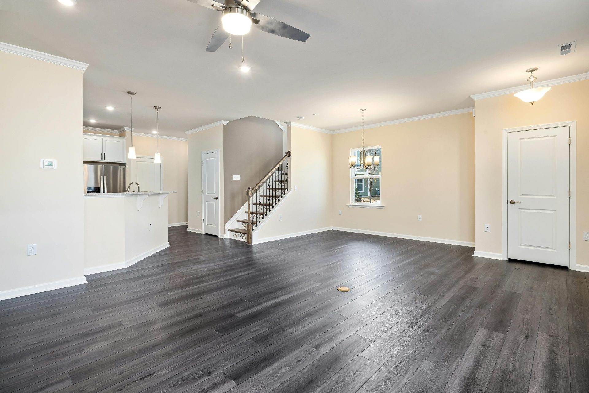 Empty modern living space with hardwood flooring and ceiling fan, ideal for new home or renovation concepts.